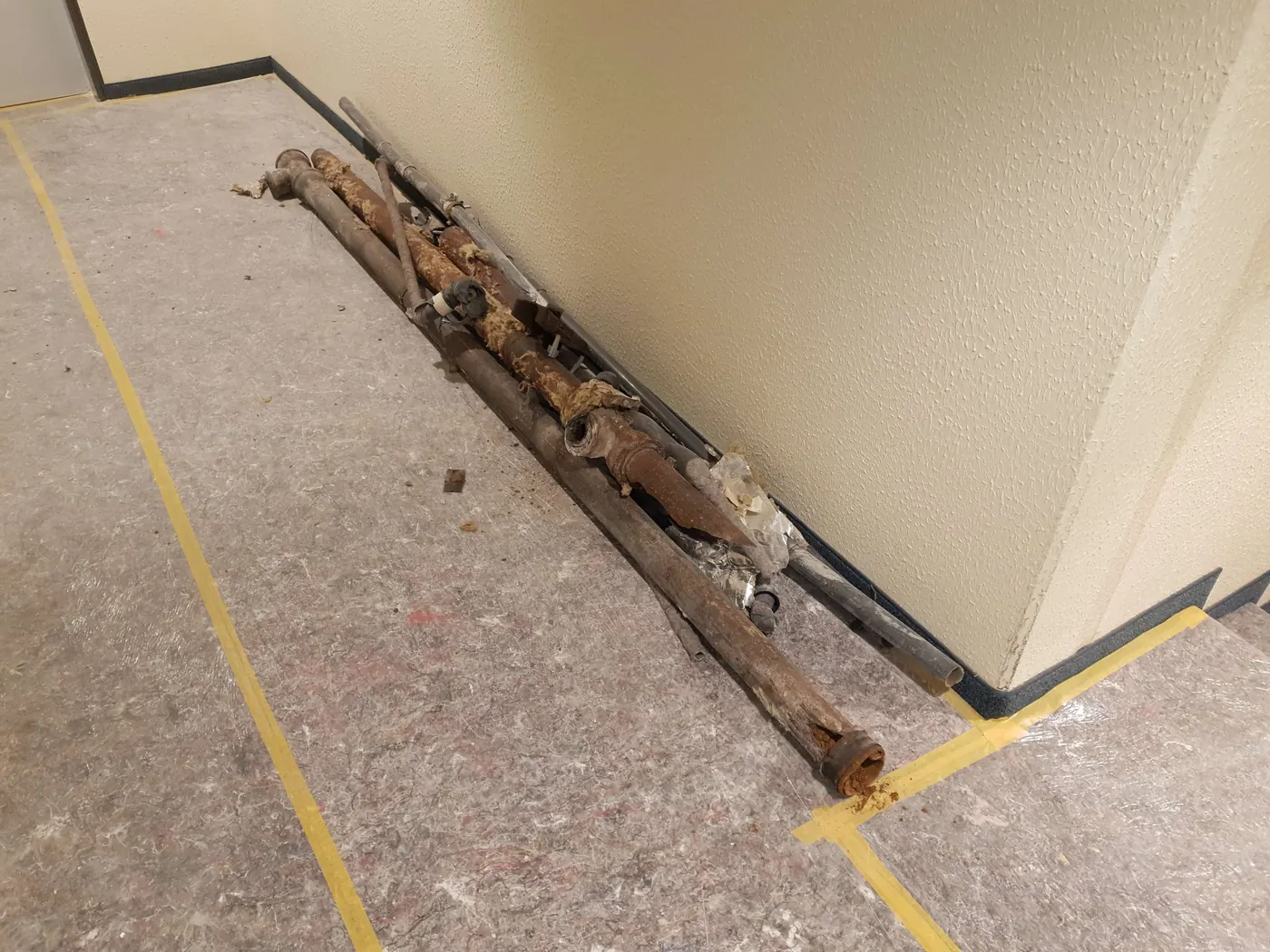 Mehrere ausgebaute alte Rohre liegen auf einem abgedeckten Flur in einem Wohngebäude
